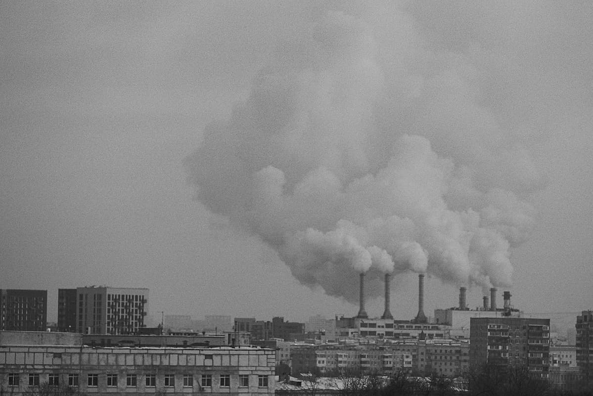 A heat and power station is producing a lot of steam on a cold winter day in Moscow. You can see a mix of apartment buildings from different eras. On the left edge of the picture are some of the newer buildings, while closer to the right are older ones.